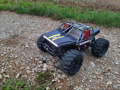 1-10 RC Shorttruck mit LED Lichtband Schwarzes RC-Auto mit großen Reifen auf einem Kiesweg.
