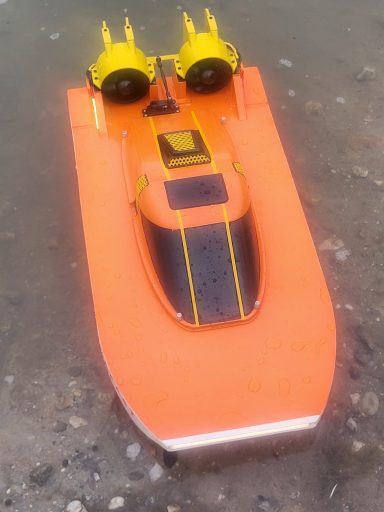 RC Doppelimpeller Boot Ein orangefarbenes ferngesteuertes Boot mit gelben Motoren auf dem Wasser.